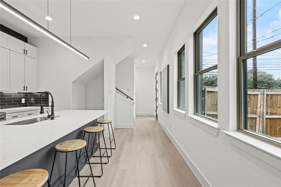 Kitchen with white cabinets, light stone counters, a healthy amount of sunlight, and a breakfast bar