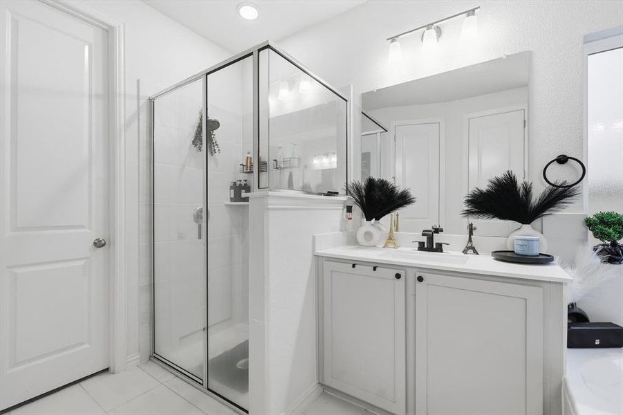 Full bathroom featuring vanity, light tile patterned flooring, and a shower stall
