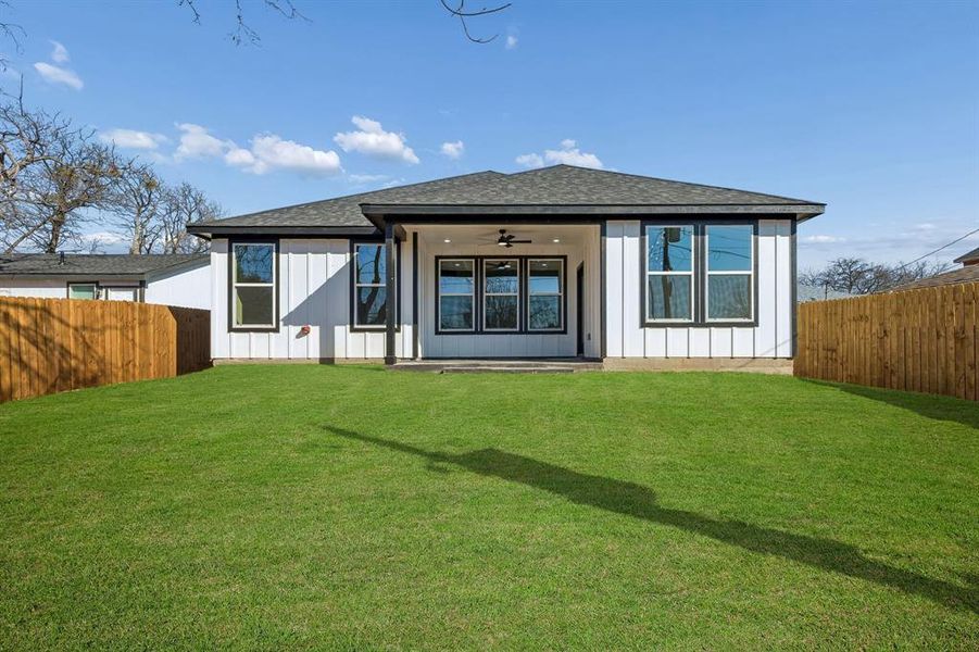 Back of property with a ceiling fan, a fenced backyard, roof with shingles, and a patio