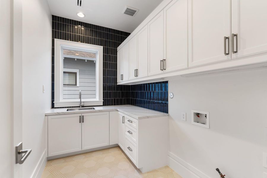 Spacious utility room with soaking sink and custom cabinetry.
