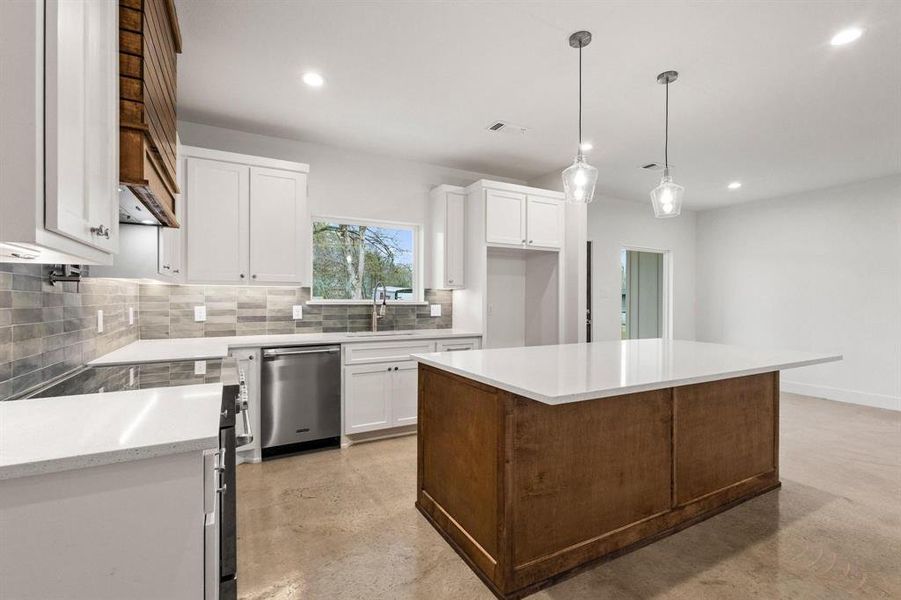 Kitchen featuring stainless steel appliances, finished concrete floors, backsplash, white cabinetry, and a center island