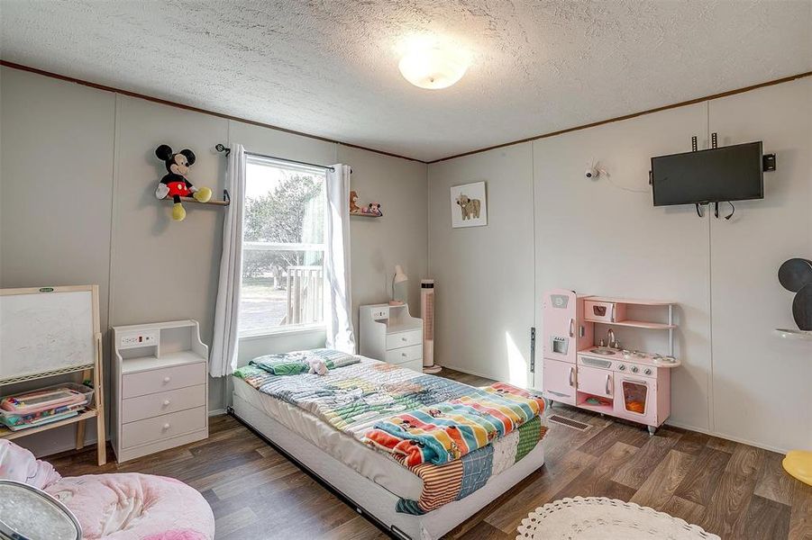 Bedroom with a textured ceiling and dark hardwood / wood-style flooring