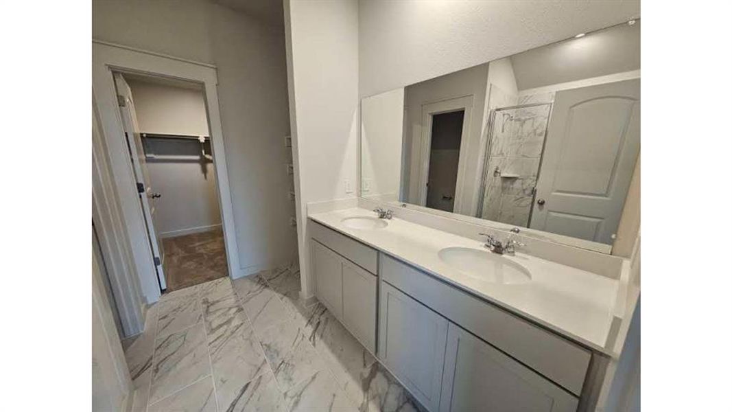 Double vanity with light gray cabinetry, integrated sinks, and polished chrome fixtures