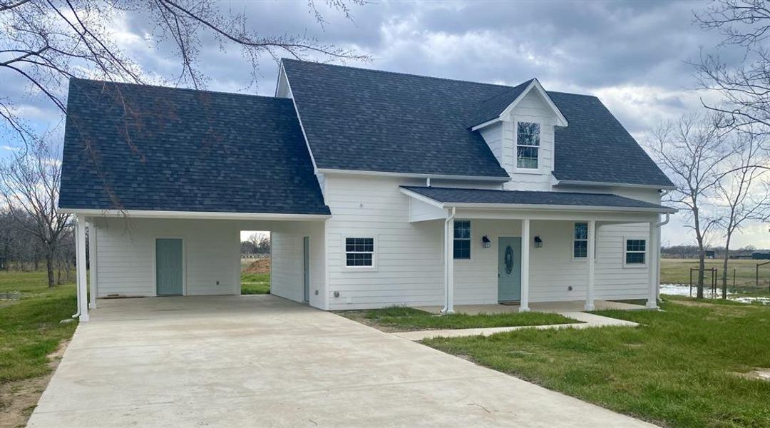 New england style home featuring a carport, covered porch, and a front yard