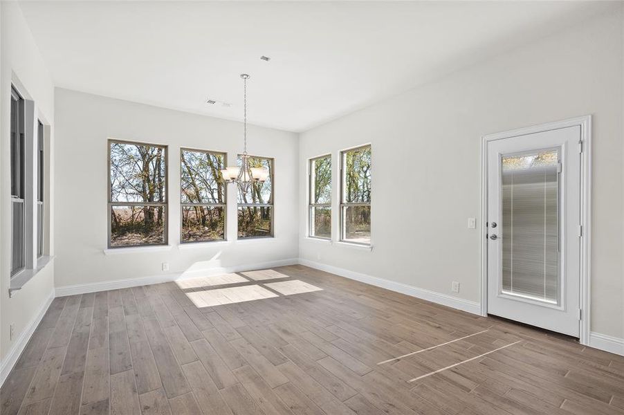 Unfurnished dining area featuring a chandelier and wood finished floors Unfurnished dining area featuring a chandelier and wood finished floors