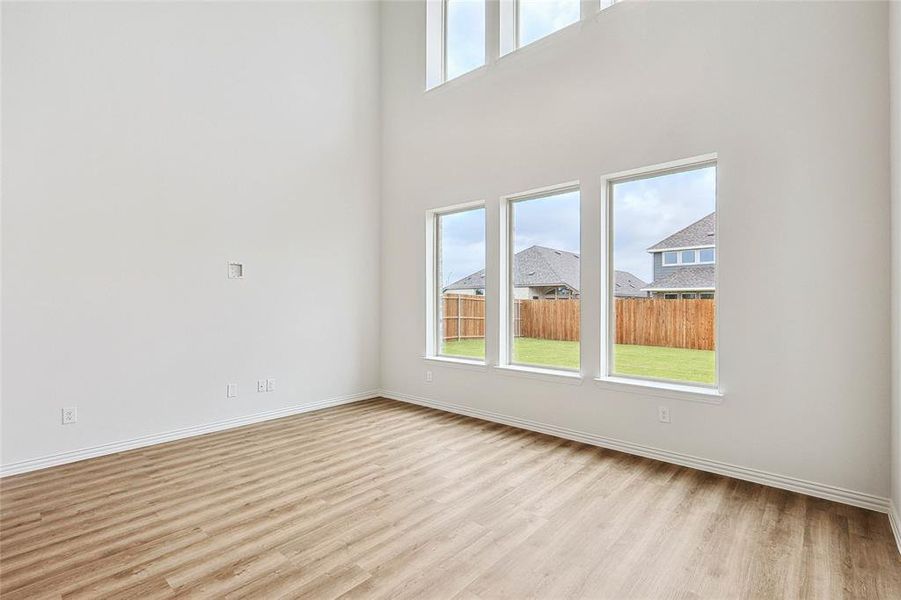 Empty room featuring a towering ceiling and light hardwood / wood-style flooring