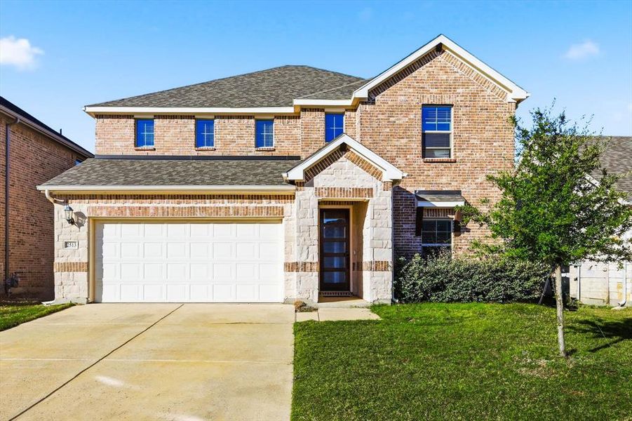 Traditional-style home with stone siding, brick siding, a shingled roof, and concrete driveway