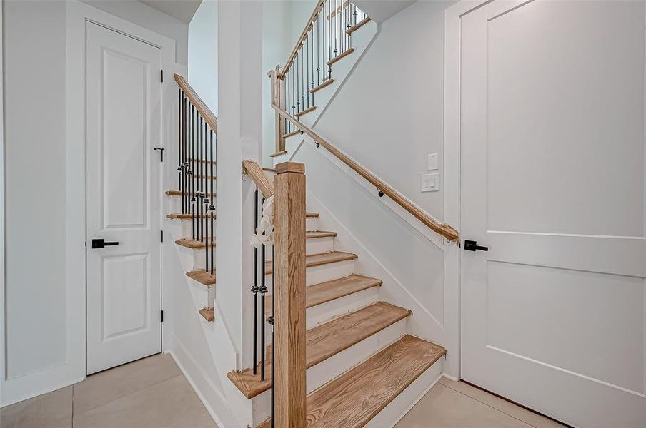 This photo showcases a modern staircase with wooden steps and sleek black metal railings, set against a backdrop of light-colored walls and doors, creating a clean and inviting entryway.