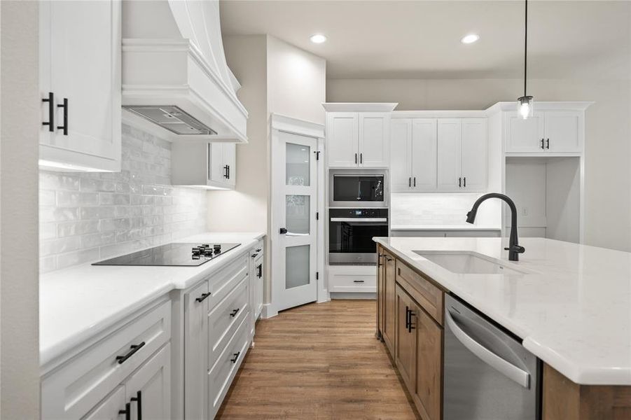 Kitchen featuring white cabinetry, decorative backsplash, brown cabinets, stainless steel appliances, and recessed lighting