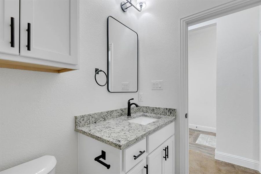 Half bathroom with vanity and a textured wall