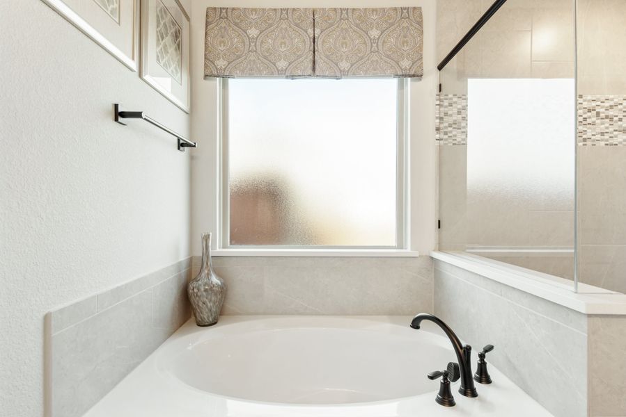 Bathroom with soaking tub, dark bronze faucet, frosted window, and glass shower enclosure nearby