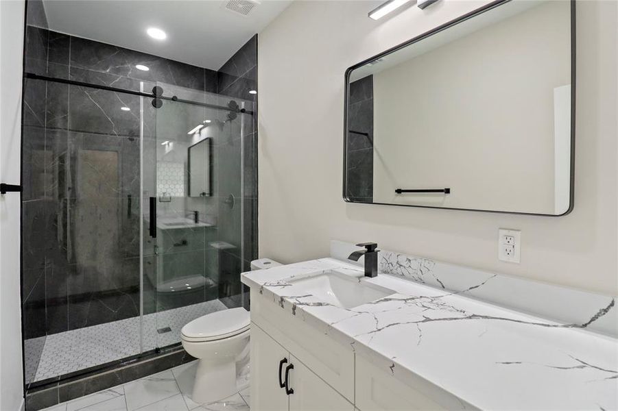 Main bathroom with stand-up tiled shower and quartz countertop.