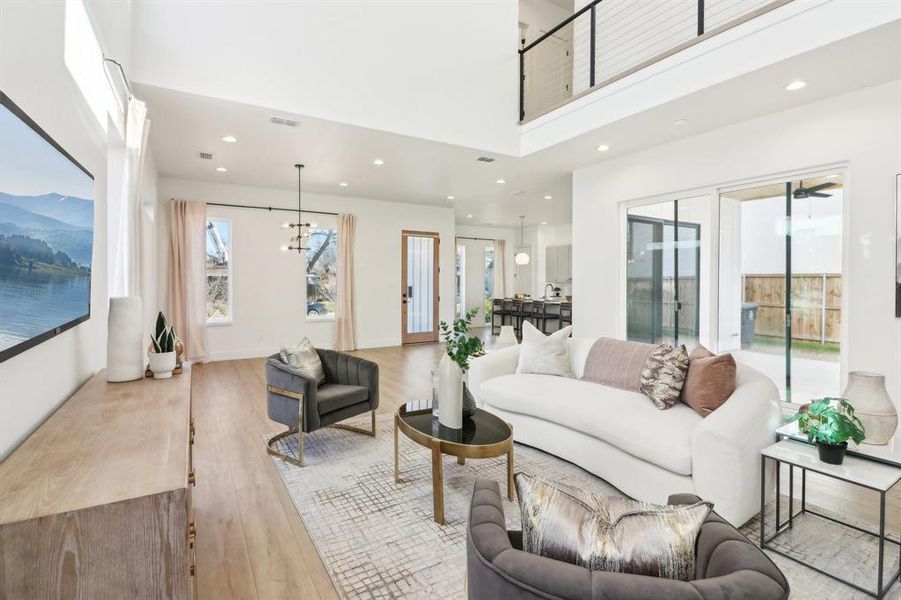 Living room with a high ceiling, light hardwood / wood-style flooring, and an inviting chandelier