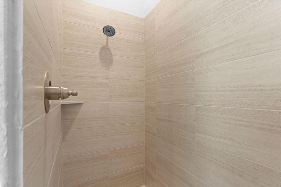 The separate shower features clean tile surrounds and a spacious layout, offering a refreshing and practical design that complements the elegant finishes found throughout the primary bathroom.