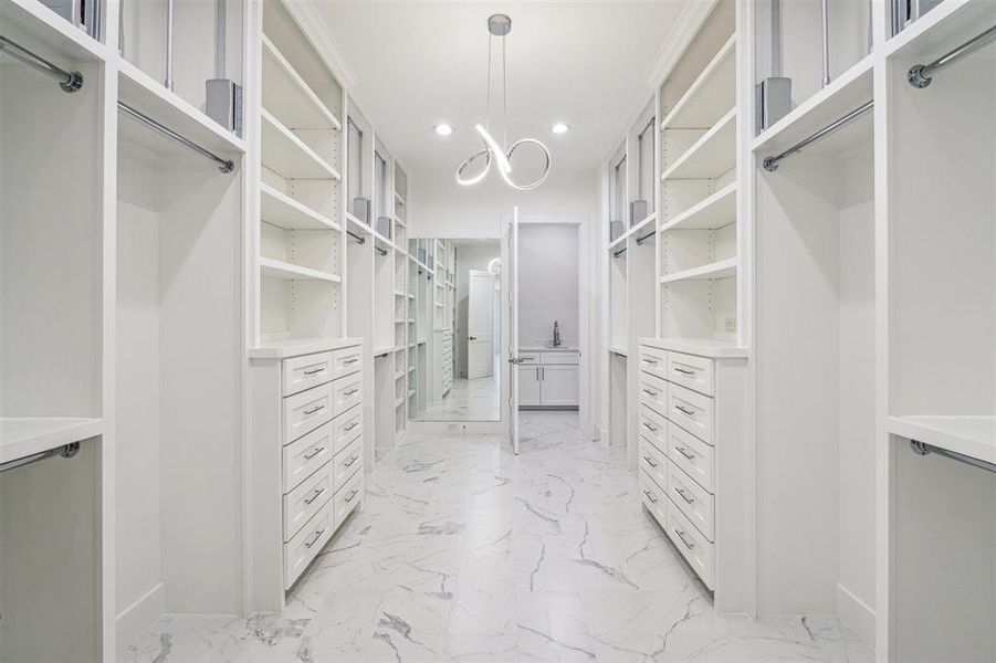 One of two primary closets with built-in cabinets and shelves.