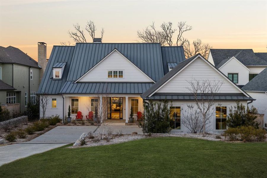 Rear view of house featuring a yard, a chimney, covered porch, a standing seam roof, and metal roof Rear view of house featuring a yard, a chimney, covered porch, a standing seam roof, and metal roof