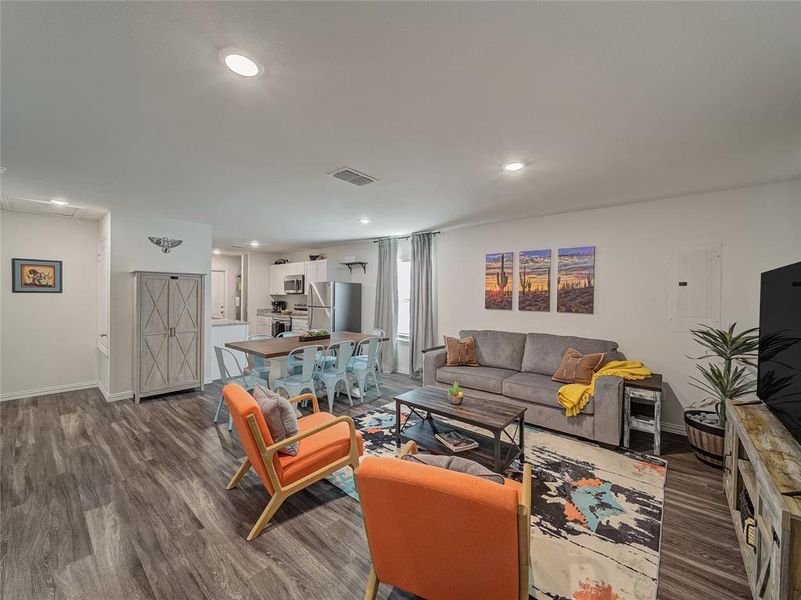 Living area with dark wood-style flooring, electric panel, and recessed lighting