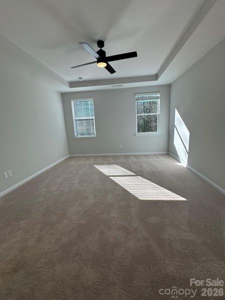 Primary bedroom with tray ceiling and fan Primary bedroom with tray ceiling and fan
