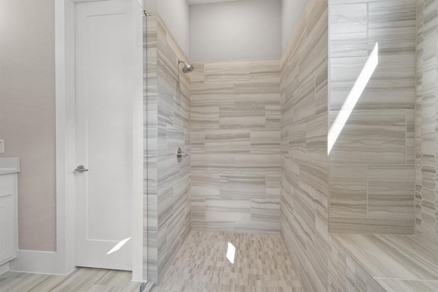A spacious, naturally illuminated shower features elegant tile work and a convenient built-in bench. A spacious, naturally illuminated shower features elegant tile work and a convenient built-in bench.