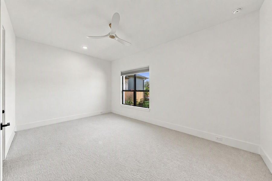 This generously sized secondary bedroom offers its own private bath, making it ideal for guests or family members alike. Soft carpet flooring and a ceiling fan add comfort throughout.