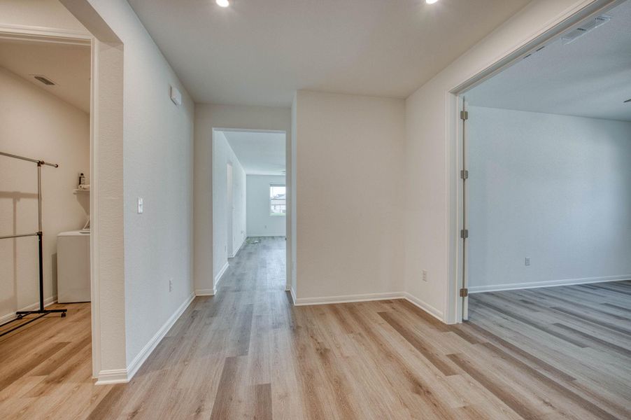 Smooth wood-look flooring connects distinct living spaces under a crisp, neutral finish.