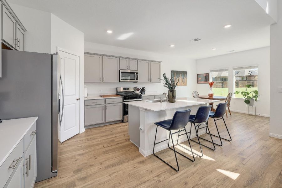 Contemporary kitchen featuring light wood-finish flooring, white countertops, and gray cabinetry Contemporary kitchen featuring light wood-finish flooring, white countertops, and gray cabinetry