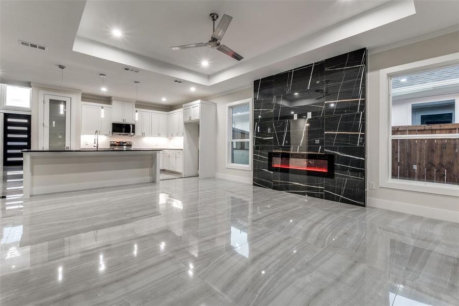 Kitchen featuring a tray ceiling, pendant lighting, white cabinets, a fireplace, and ceiling fan