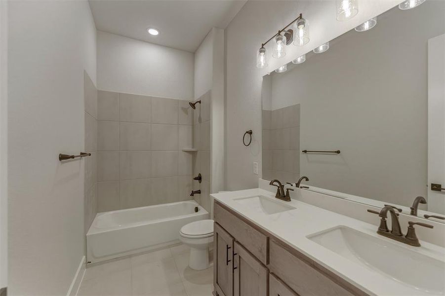 Bathroom featuring a double vanity with integrated sinks, a full-width mirror, and bronze-finish fixtures Bathroom featuring a double vanity with integrated sinks, a full-width mirror, and bronze-finish fixtures