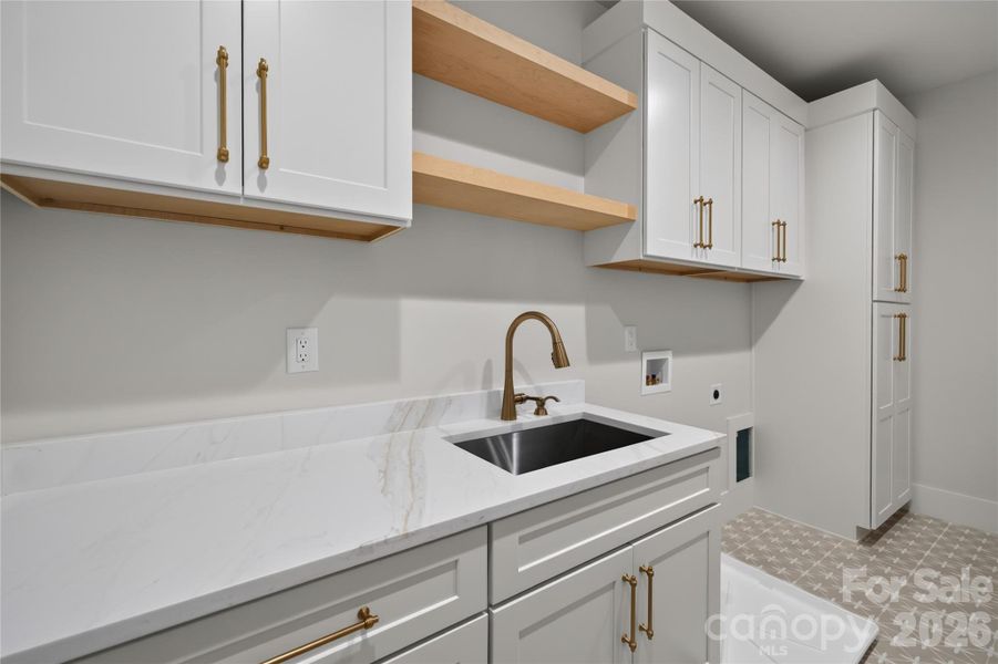 Huge laundry- picture doesn't do it justice! Mud sink, tons of cabinetry, maple shelving, quartz countertops