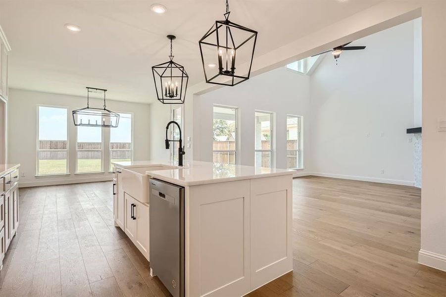 Kitchen with a wealth of natural light, white cabinets, dishwasher, light hardwood / wood-style floors, and a center island with sink