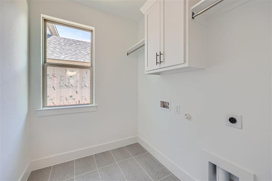 Washroom featuring electric dryer hookup, tile flooring, washer hookup, and cabinets