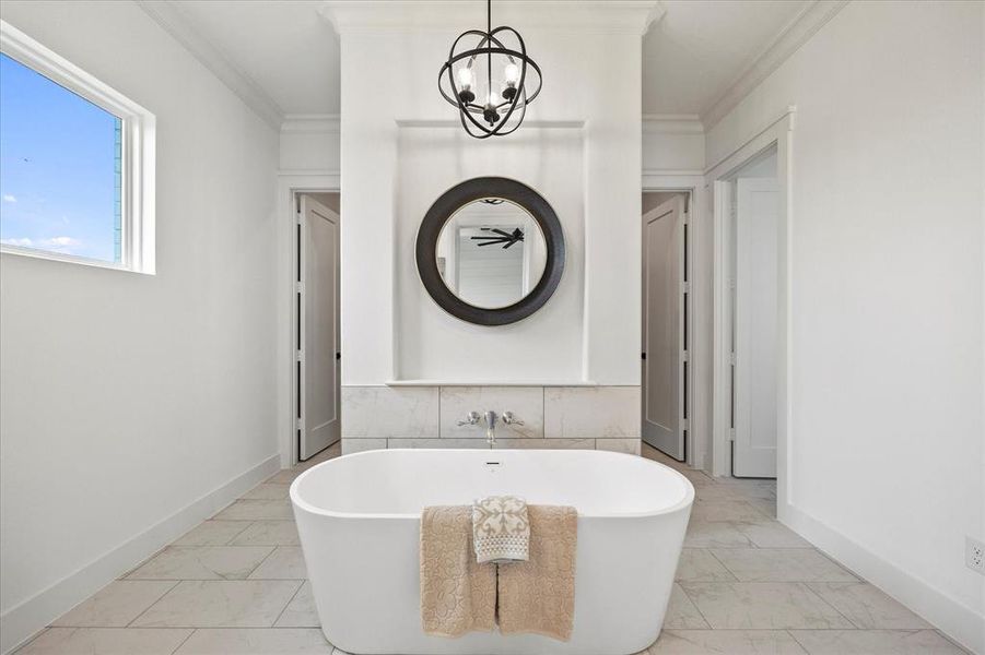 Bathroom featuring a notable chandelier, ornamental molding, a bathtub, and tile patterned flooring