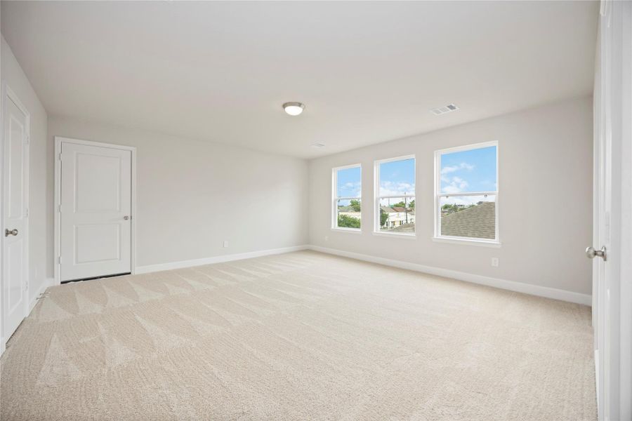 A remarkably large third-floor bedroom basks in brightness, featuring an ensuite bathroom and access to a substantial walk-in storage closet, ensuring privacy and comfort.