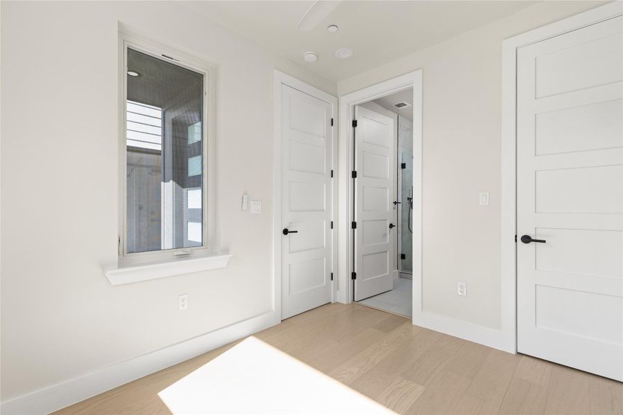 Clean lines and light wood flooring define this serene bedroom space with an attached bath.