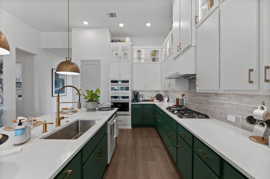 Dual tone kitchen with glass insert cabinets, dark wood finished floors, light stone counters, backsplash, and two tone cabinets Dual tone kitchen with glass insert cabinets, dark wood finished floors, light stone counters, backsplash, and two tone cabinets