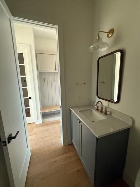 first floor powder bathroom with vanity and hardwood / wood-style flooring