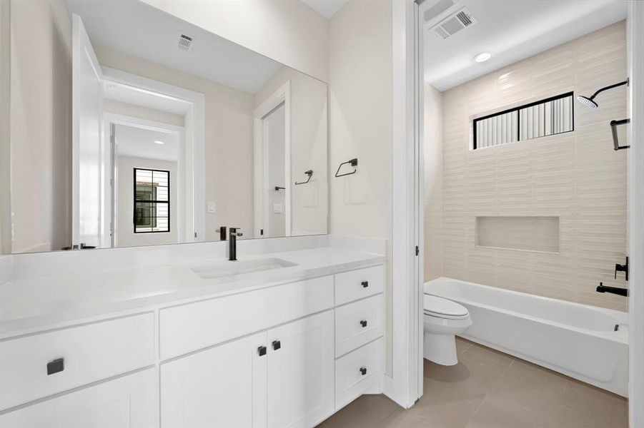 Third floor full bath includes quartz counter, dimensional wall tile, product niche, and modern black fixtures.