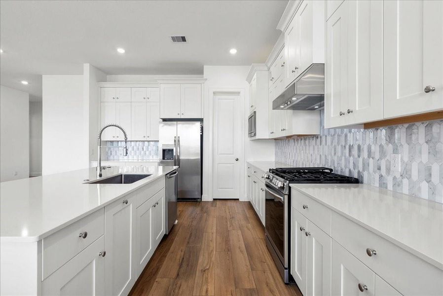 The chef’s eat-in island kitchen is the heart of the home, featuring lengthy quartz countertops, an abundance of upgraded cabinetry with crown molding, a designer backsplash, and stainless steel appliances. The chef’s eat-in island kitchen is the heart of the home, featuring lengthy quartz countertops, an abundance of upgraded cabinetry with crown molding, a designer backsplash, and stainless steel appliances.