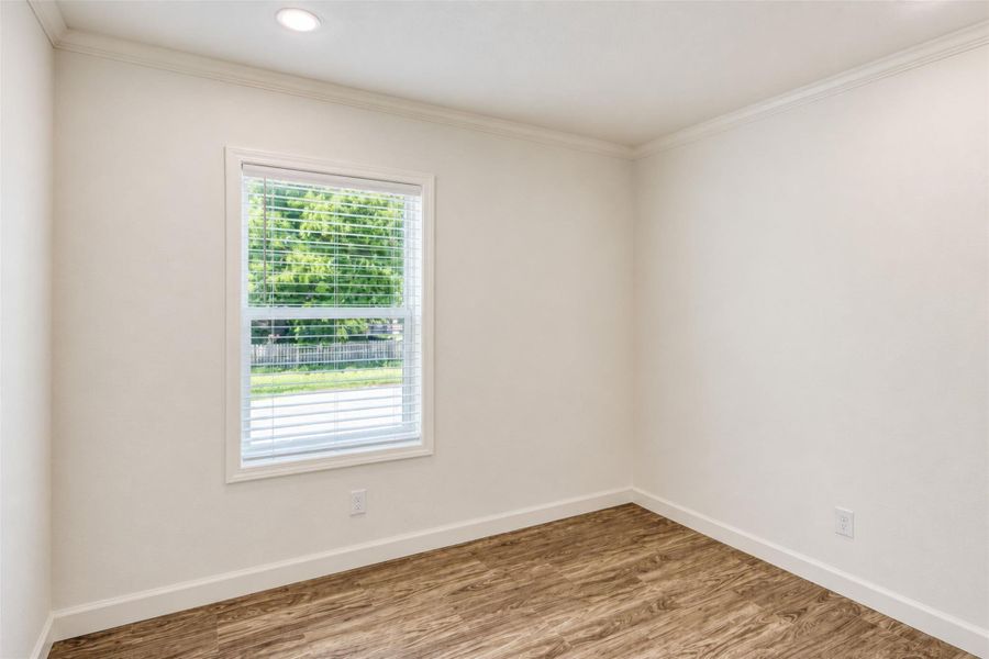 A well-lit bedroom features durable laminate flooring and a bright window with privacy blinds. A well-lit bedroom features durable laminate flooring and a bright window with privacy blinds.