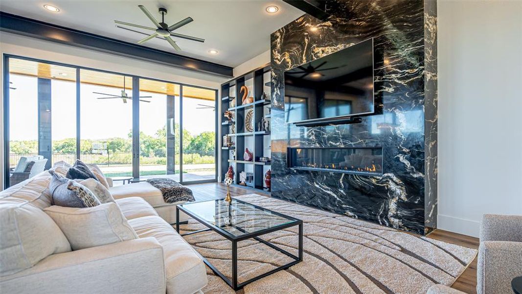 Living room featuring a premium fireplace, hardwood / wood-style floors, and ceiling fan