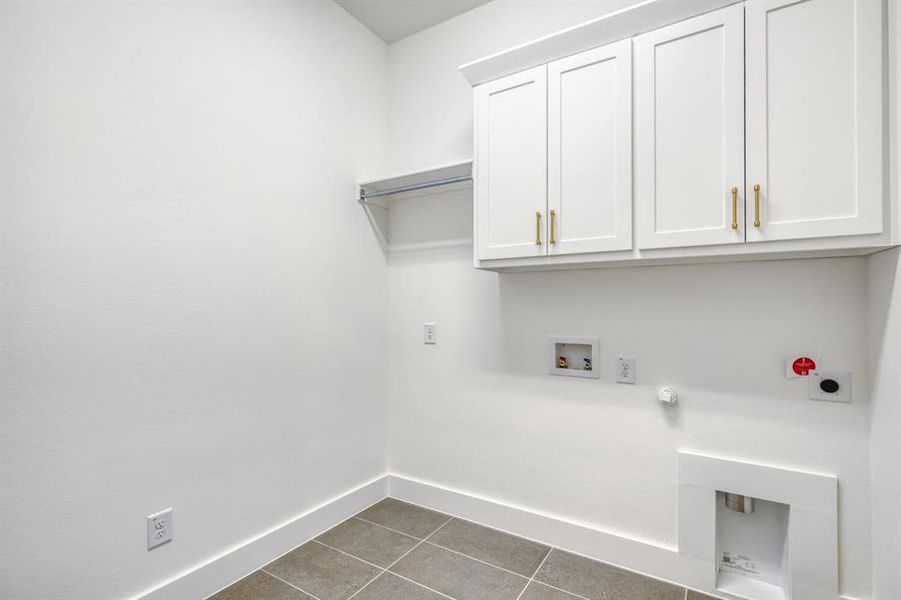 Laundry area featuring hookup for a gas dryer, dark tile patterned flooring, washer hookup, cabinet space, and electric dryer hookup