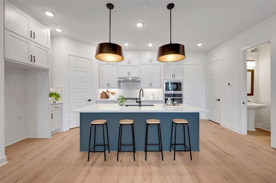 Modern kitchen featuring a blue island with a white countertop, two pendant lights, recessed lighting, and wood-finish flooring Modern kitchen featuring a blue island with a white countertop, two pendant lights, recessed lighting, and wood-finish flooring