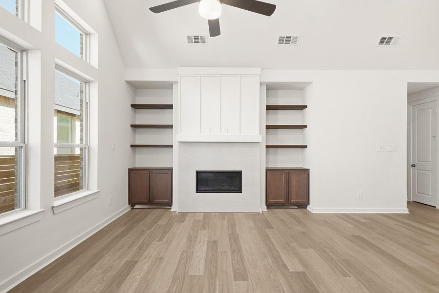 A spacious family room featuring a cozy fireplace, built-in shelves and cabinets, and soaring high ceilings for an elegant touch. A spacious family room featuring a cozy fireplace, built-in shelves and cabinets, and soaring high ceilings for an elegant touch.