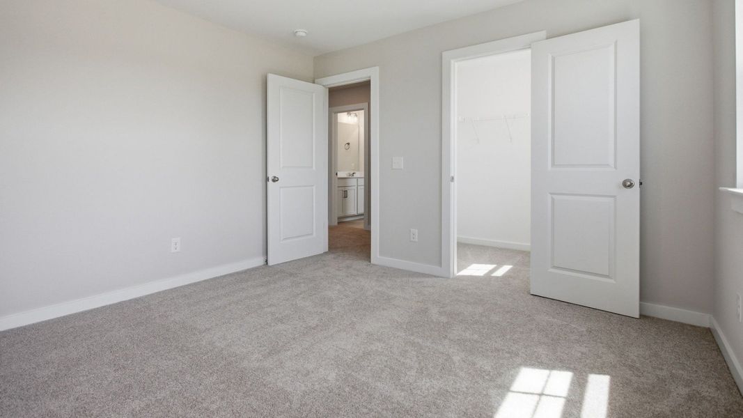 Bedroom with carpet, walk-in closet, and nearby bathroom Bedroom with carpet, walk-in closet, and nearby bathroom