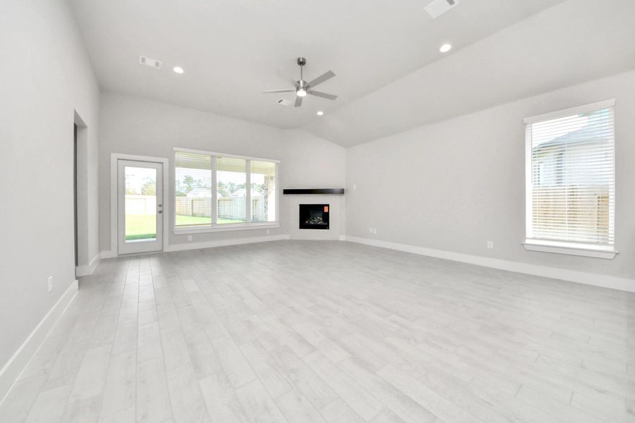 Welcome family and guests to your charming living room! With its high ceilings, recessed lighting, ceiling fan, custom paint, beautiful flooring, and large windows that let in abundant natural light, this room is perfect for gatherings. Sample photo of completed home with similar floor plan. Actual colors and selections may vary.