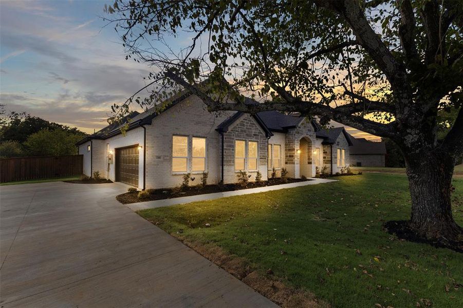 View of front facade featuring driveway, brick siding, and an attached garage