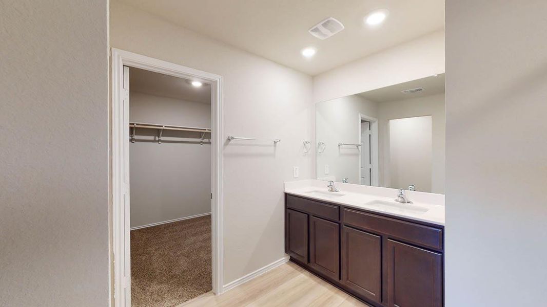 Full bath featuring double vanity, a walk in closet, recessed lighting, and light wood-style floors