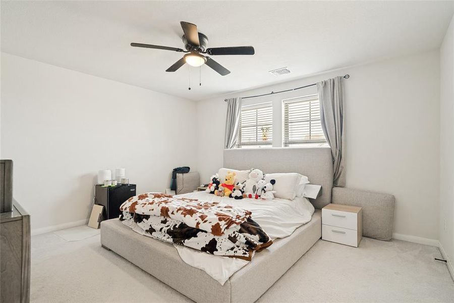 Spacious bedroom featuring light-colored carpeting and a contemporary ceiling fan with integrated lighting