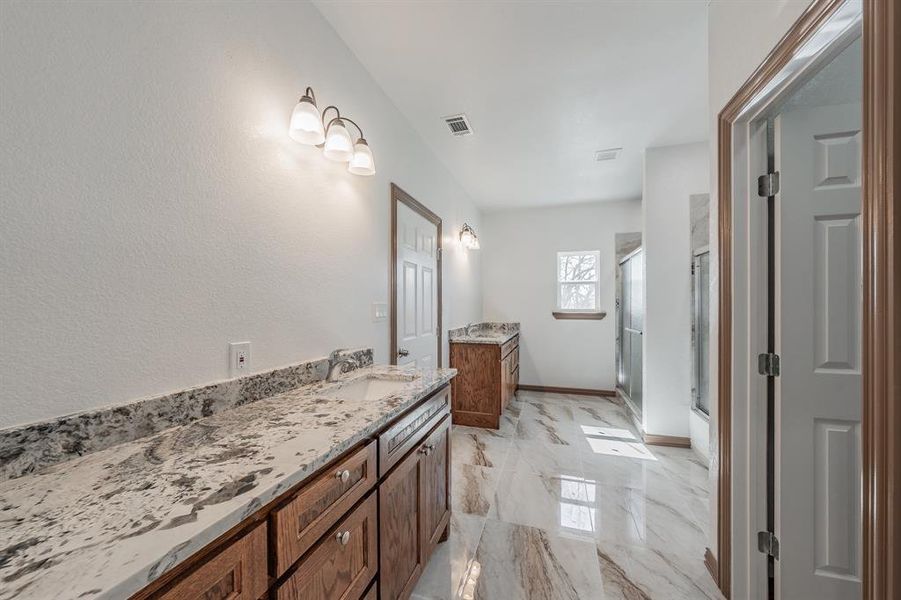 Full bath featuring marble finish floor, visible vents, vanity, a shower stall, and baseboards