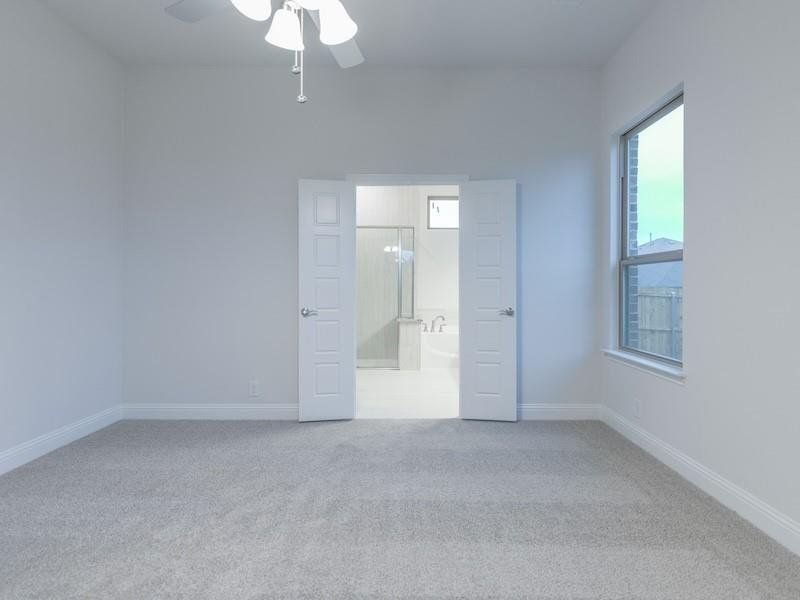 Unfurnished bedroom with ceiling fan, connected bathroom, and light carpet